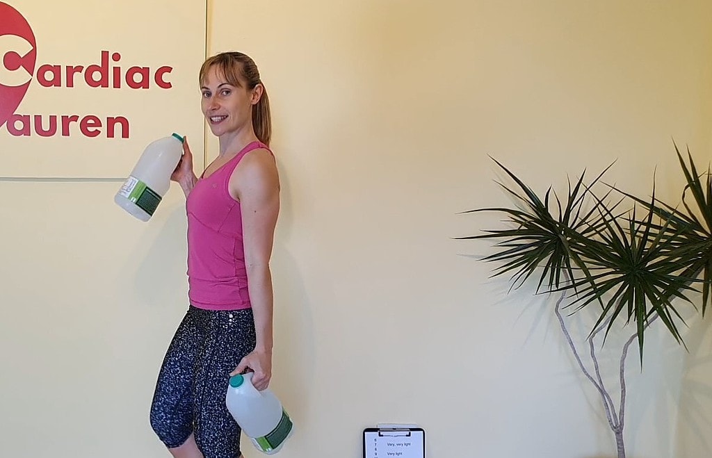 Standing biceps curl with milk bottles as weights, healthcare professionals